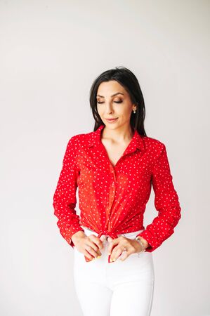 Fashion posing. Beautiful girl in trendy wear looks down, she is on a white background indoorsの写真素材
