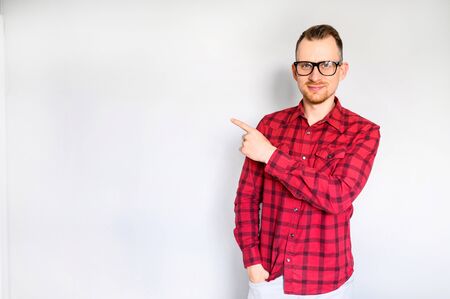 Look here. Young hipster in casual wear points finger at blank space. Mockup, copyspaceの写真素材