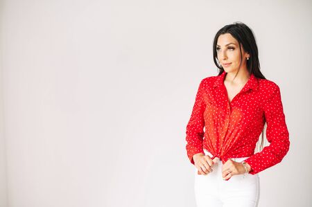 Fashion posing. Beautiful girl in trendy wear looks away, she is on a white background indoors. Copyspaceの写真素材