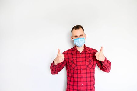 Protect yourself during pandemic. A young man showing thumbs up on medical mask on his face. Saving from allergic, smog, virusの写真素材