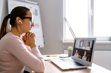 Side view on woman talking with employees via video call. Several webcam shot of people on laptop...