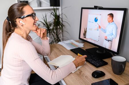 Webinars, lectures online. A woman in office is watching online classes, male teacher on laptop...