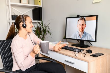 Video conversation with employee. A young woman using headset for talking online with male coworkerの写真素材
