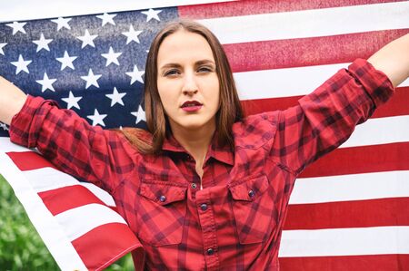 Upset woman is holding hands up with american flagの写真素材