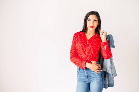Charming slim girl with jeans and a red shirt posing on a white backgroundの写真素材