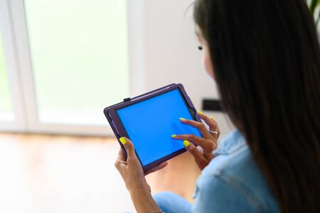 Back view female hands hold a digital tablet computer with a blank screen. Copy space for text, mock-upの写真素材