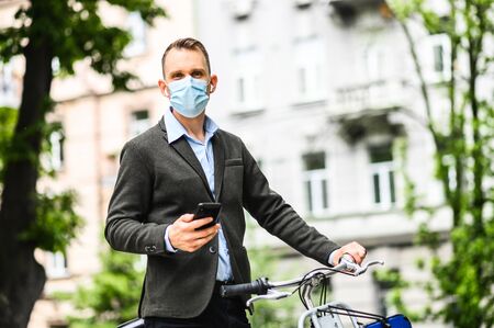 A guy in a medical mask on the bicycle is using phoneの写真素材