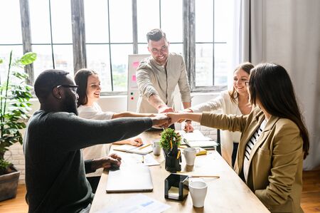 Young creative multiracial team at the office. Their fists stacked together, sign and symbol of teamwork, for success deal,union,collaborationの写真素材