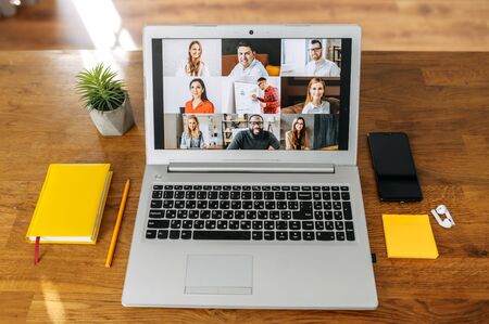 Video meeting. Laptop on the table, video call with group of people on the screen, app for video communication. No people in the roomの写真素材