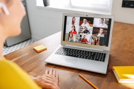 Communication on distance via video, video call. A young woman using app on laptop for meeting with friends or coworkers. Back viewの写真素材