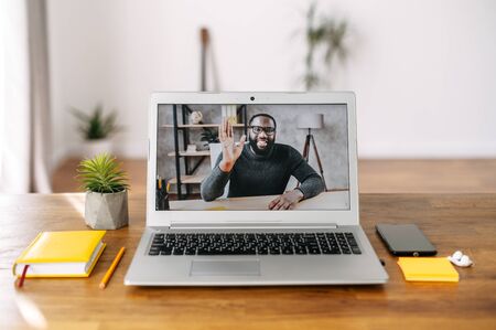 Online talking with employee, coworker. An African-American guy on the laptop screen indoor. Nobody in the roomの写真素材