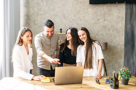 Employees discuss working moments in front of a laptop in a friendly atmosphere, smiling and laughingの写真素材