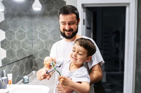 Father and son have a fun while brush teeth together, they toothbrushes fightの写真素材