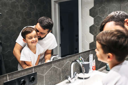 A good morning at home. Father and his little son wash up together in the bathroom, they look in the...