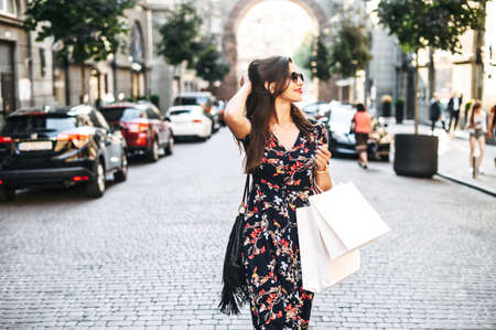 Marvelous young woman is walking on the city street with a paper shopping bags in her hands, she has shopping dayの写真素材