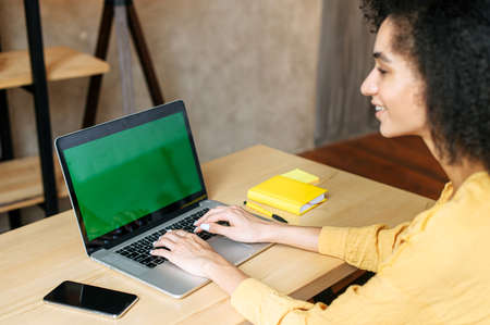 Back view a mixed-race girl types on the laptop keyboard, a laptop with a blank screen. Copy space, mockupの写真素材