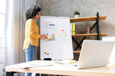 An african-american female woman conducts online webinars, video training. The woman with flip chart...