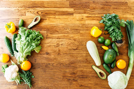 Various fresh vegetables are laid out on the table, on the left and right edges of the frame. Vegetarian food concept. Copy Space, mockupの写真素材