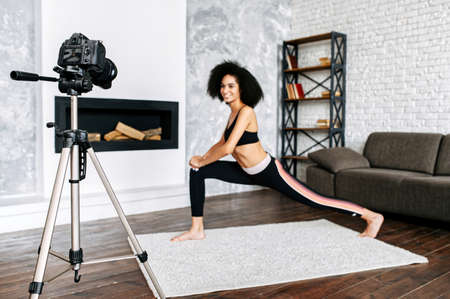 Professional camera records an African-American woman doing sports training at home, the woman is out of focus. Sports vlogging conceptの写真素材