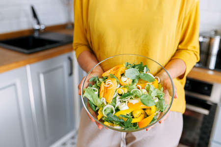 Female hands are holding a bowl full of fresh salad. Healthy and tasty mealの写真素材