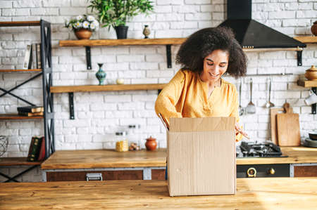 A young multi-racial girl received an online delivery order. Attractive woman with Afro hairstyle...