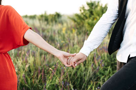 Love story outdoors. A hands of lovers hold each otherの写真素材