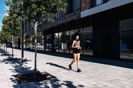 Full length of beautiful mixed-race woman running on the city streeの写真素材