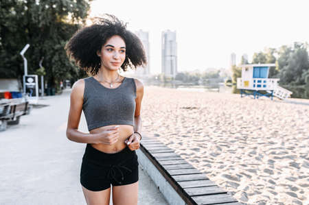 Attractive athletic African-American girl running on the waterfront. The concept of a healthy lifestyleの写真素材