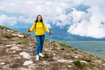 Young attractive woman with nordic walking poles hiking outdoors. Hiking and resting in mountainsの写真素材