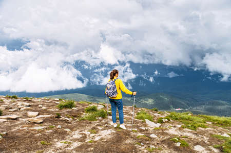 Backpacking in the mountains. Back view of a female hiker with a panoramic viewの写真素材