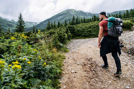 Male tourist hiking in a mountains. A guy with a big backpack walks with a stunning landscape on the backgroundの写真素材