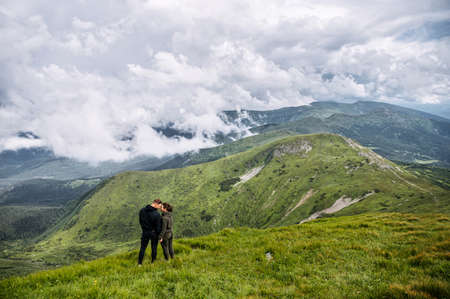 Back view of couple lovers stands on the top of the hill, panoramic mountain view on the backgroundの写真素材