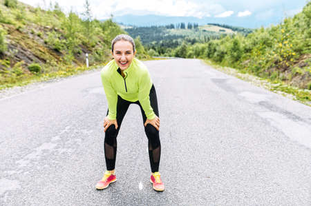 Healthy young woman rest after sprint outdoors. Running in the mountainsの写真素材