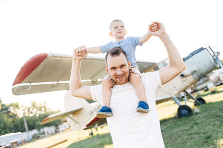 A dad and toddler spend time outdoors in an airplanes museum. A young father carries baby boy on his...