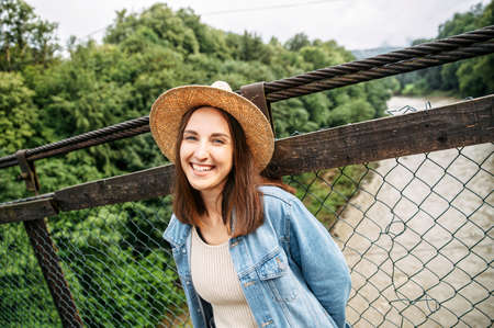 Natural beauty. A young woman in hat and jeans jacket outdoors. A girl in casual wear flirty looks into cameraの写真素材