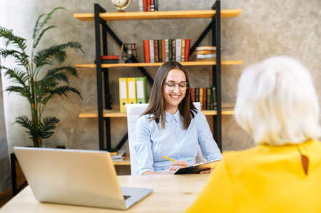 An older woman has a job interview. Young female employee from hr department is interviewing senior female applicant in the office.の写真素材