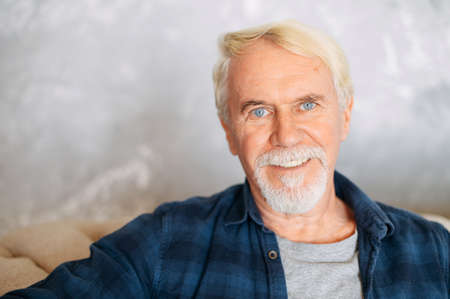 Portrait of handsome mature bearded man with gray hair. A senior man with a blue eyes and pleasant smile looks at cameraの写真素材