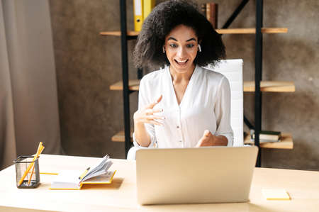 Charming female office employee has online video meeting on laptop.の写真素材