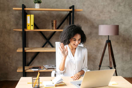 A beautiful black woman in smart casual wear is using laptop  for video callの写真素材