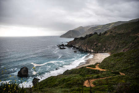 Panoramic ocean view in the cold and cloudy day, green hills and a sandy bay of California, USAの写真素材