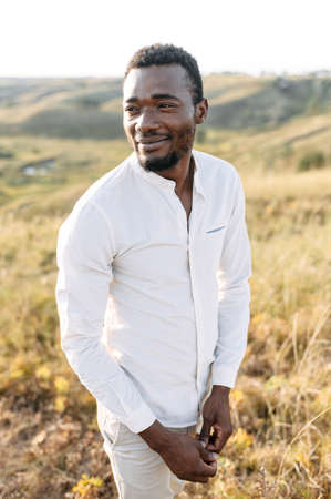 A handsome black guy in white wear walking on the meadowの写真素材