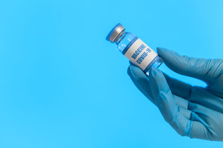 Hand of a medic in glove holds a vaccine