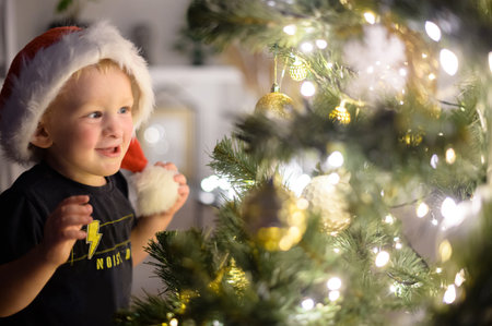 A cute toddler in santa hat near Christmas tree