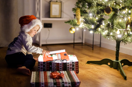 A cute boy with a gift box near Christmas treeの写真素材