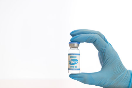 A bottle of new pfizer vaccine in hand on whiteのeditorial素材