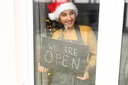Young woman holding open sign in cafeの写真素材