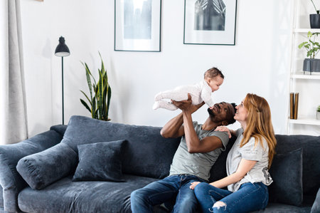 Multiracial family with baby girl sit on the couchの写真素材
