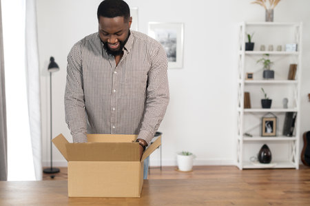 A guy is unpacking a parcel box at homeの写真素材