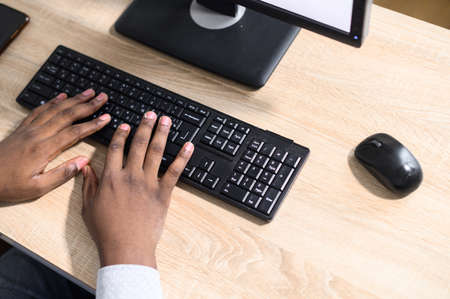 Top view hands of an African-American guy typing on the laptop keyboard. Close-up fingers typing,...