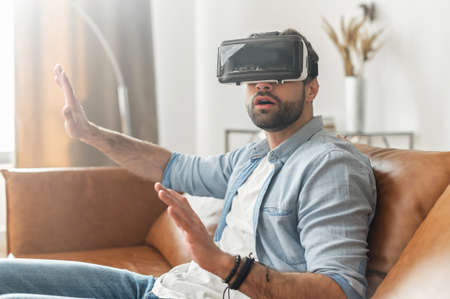 An impressed guy wearing VR headset goggles wondering how virtual world is realistic, a young man...